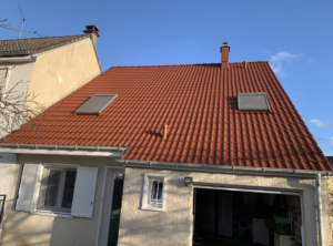 Maison avec une toiture neuve. la toiture couvre la maison et le garage. Sur la toiture, il y a deux fenêtres de toit et une cheminée
